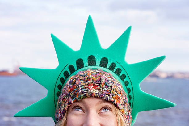 Woman wearing a tourist Statue of Liberty crown on island Close up portrait of a young blonde woman wearing a green Statue of Liberty crown. statue of liberty statue liberty new york city stock pictures, royalty-free photos & images