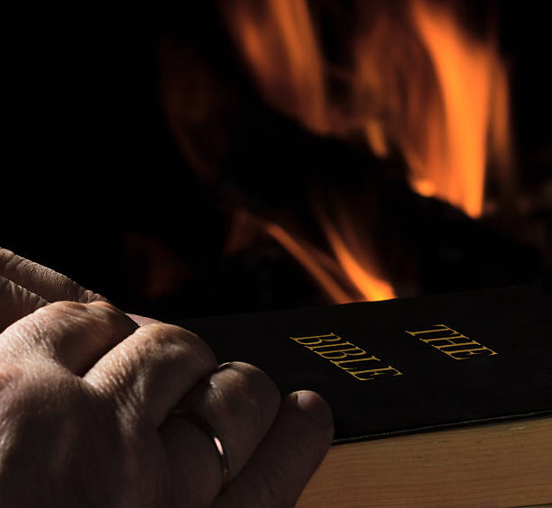 istock Hands of a man praying over Bible 452514649