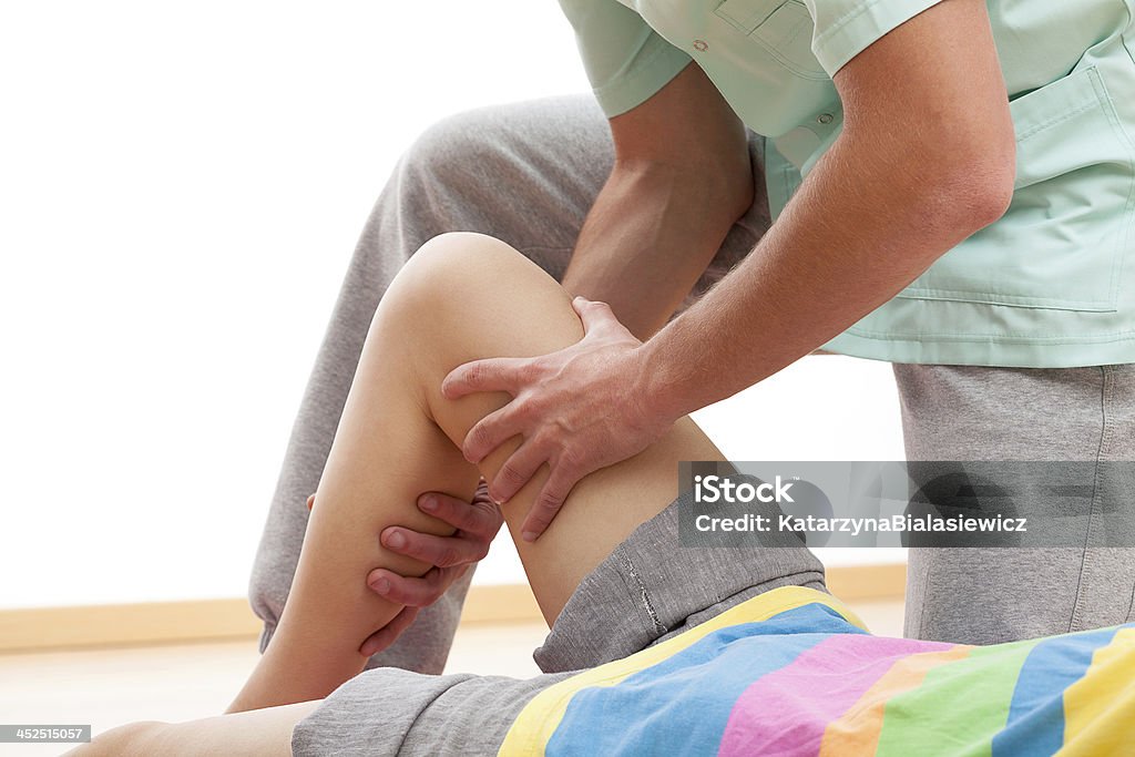 Leg massage Physiotherapist dressed in green uniform is massaging wasted leg muscles Adult Stock Photo