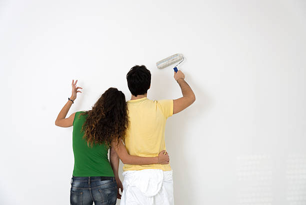 pareja joven pintura de una habitación - home improvement couple painting real estate fotografías e imágenes de stock