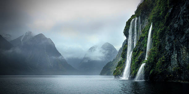 Doubtful Sound, Fjordland in New Zealand Beautiful waterfalls on a cloudy day in the Sounds tasman sea stock pictures, royalty-free photos & images