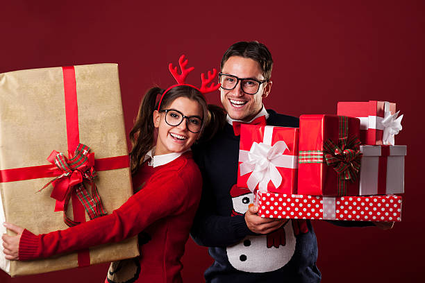 Happy nerd couple holding a lot of christmas presents Happy nerd couple holding a lot of christmas presents vintage nerd with reindeer sweater stock pictures, royalty-free photos & images