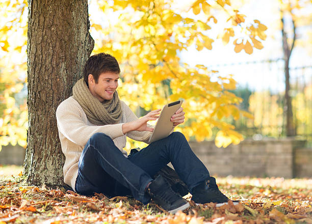 istock man with tablet pc in autumn park 452523285