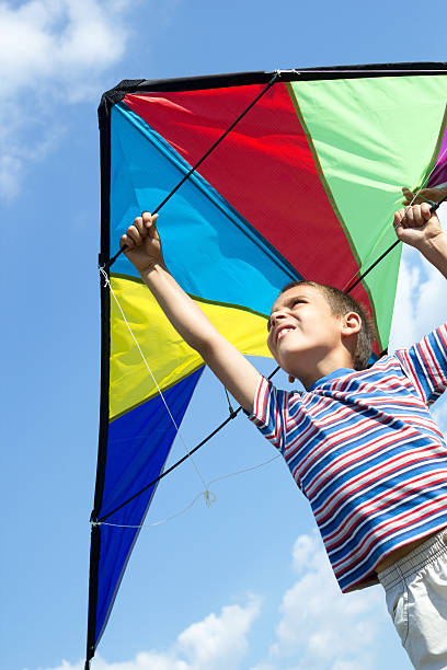 istock Little boy flies a kite into the blue sky 452533369