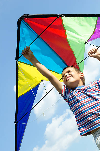 istock Little boy flies a kite into the blue sky 452533877