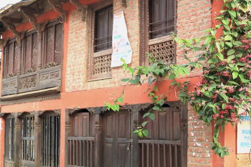 Red brick old house in the traditional newari style with carved wood doors-jambs-balconies-window shutters and roof beams. Bandipur town-Tanahu District-Gandaki Zone-Nepal.