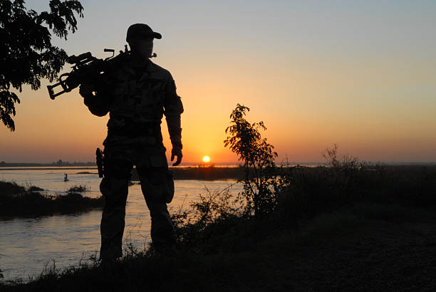 Soldier standing with gun in his shoulder a spcial french soldier front of a sunset in africa mali stock pictures, royalty-free photos & images