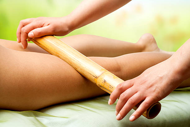 Ręce masażu kobieta nogi z bambusa. – zdjęcie