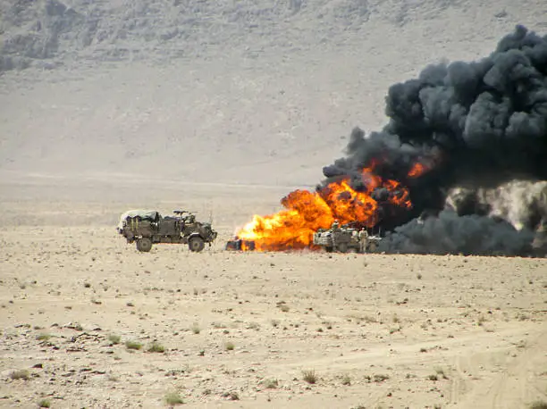 Military vehicles inspecting destroyed vehicle