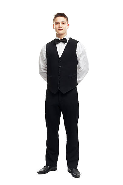 Full length portrait of young smiling waiter Full length portrait of young smiling waiter standing with hands behind his back isolated on white background hands behind back stock pictures, royalty-free photos & images