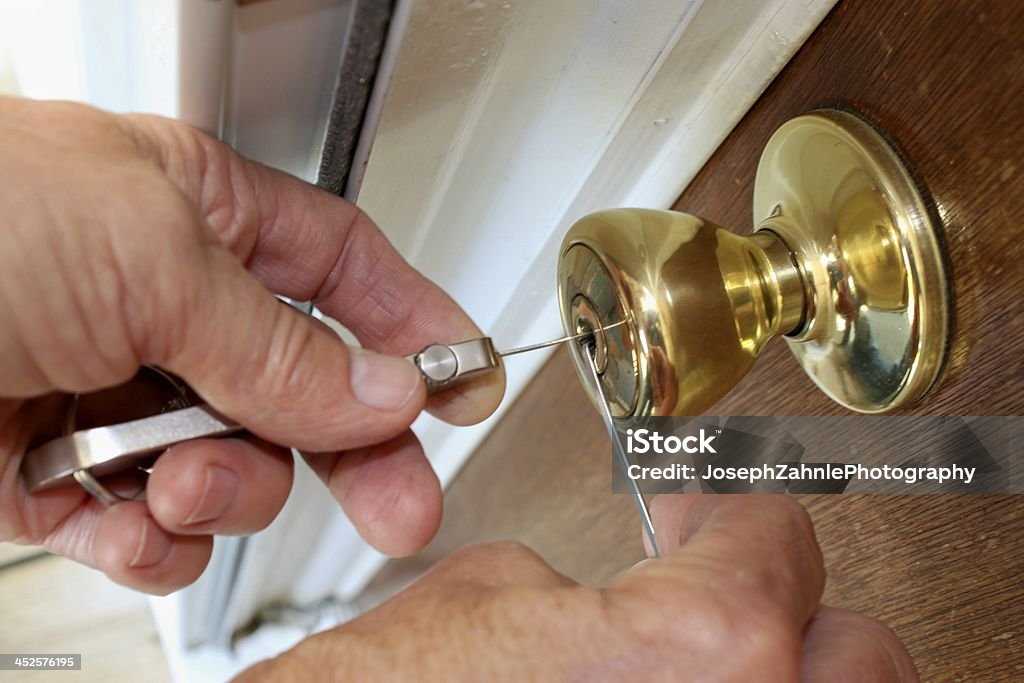 Closeup of locksmith picking a gold lock Locksmith unlocking a door. Locksmith Stock Photo