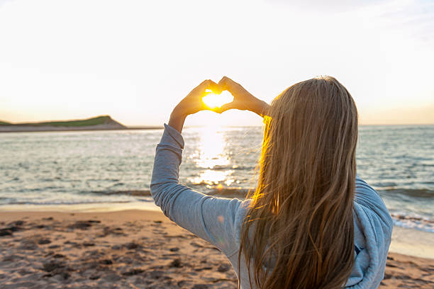 istock Girl holding hands in heart shape at beach 452578531