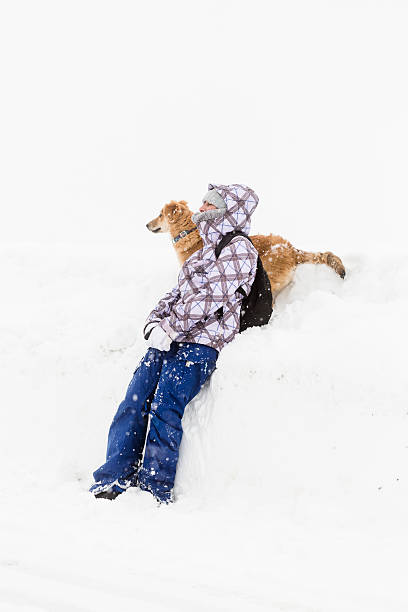istock Woman playing with her dog during a Snowfall 452586195
