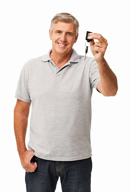 Portrait of smiling mature man showing new car key against white background. Vertical shot.