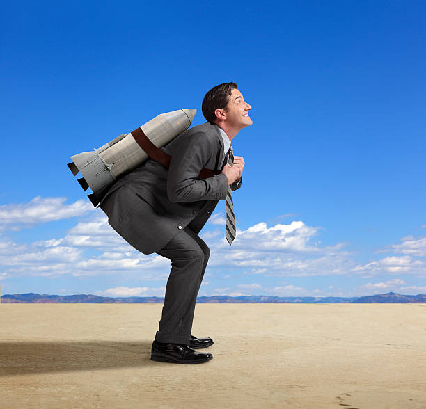istock Businessman standing with rocket strapped to his back in desert 452586661