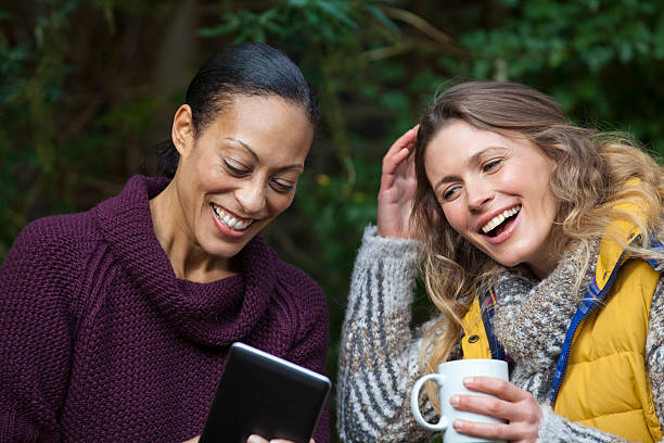 istock Two laughing friends with coffee and tablet 452589539
