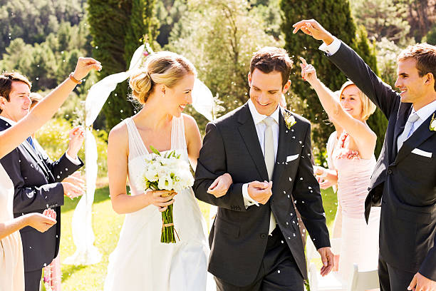 Bride and groom procession after wedding Happy couple walking while guests throwing confetti on them during wedding ceremony. Horizontal shot. newlywed photos stock pictures, royalty-free photos & images