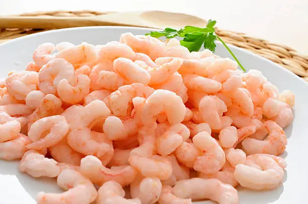 closeup of a plate with shelled raw shrimps