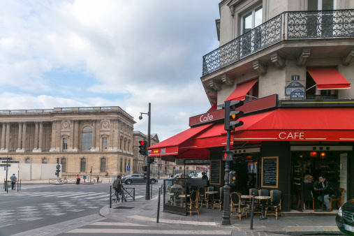Postcard view at classic street cafe-shop in Paris, France (the building on the left hand is Louvre)