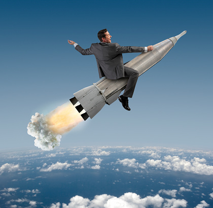 An excited businessman riding on a space rocket with exhaust and smoke plume trailing out the end of the rocket.  The rocket is high above earth, with clouds below, about to enter into orbit. Vantage point is high enough to see the curvature of the earth.