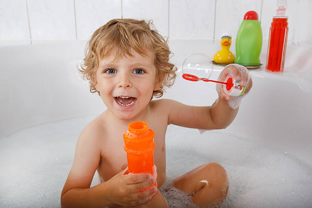 istock Adorable blond toddler boy playing with soap bubbles in bathtub 452632677