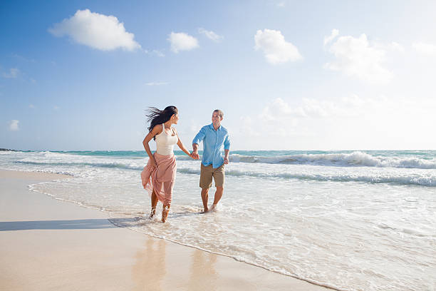 Couple walking and holding hands at a beautiful beach stock photo