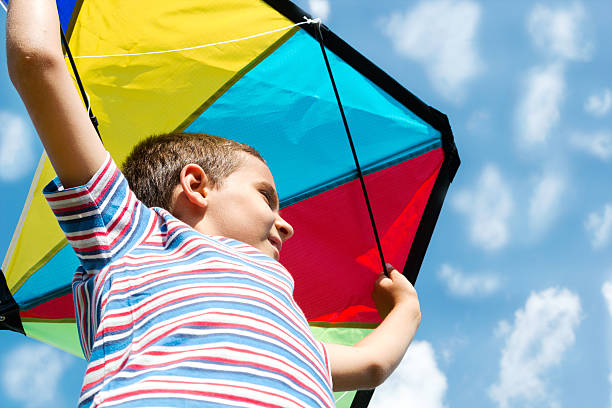 istock Little boy flies a kite into the blue sky 452638155