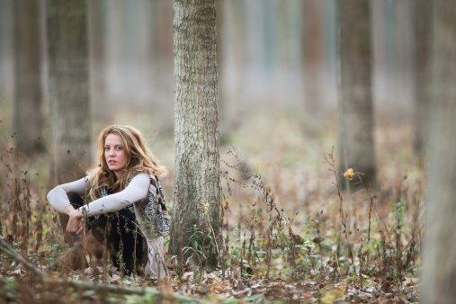 Young woman siting in forest in Autumn
