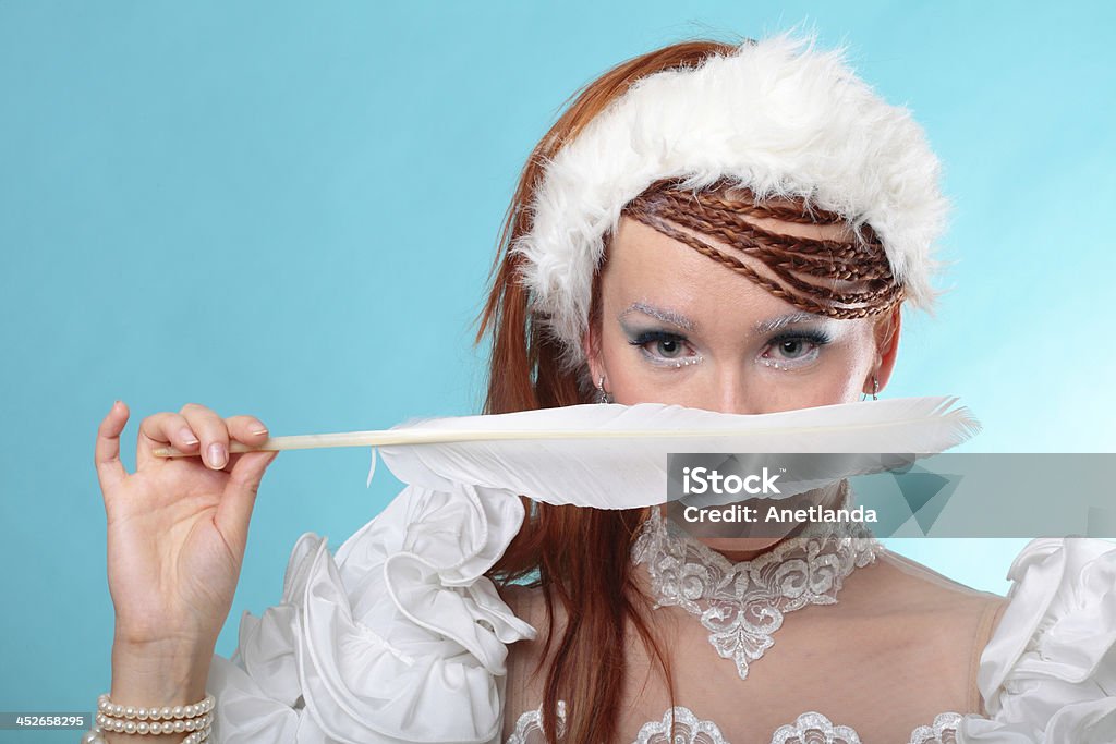 Beautiful ginger in a dress of Snow Queen Beautiful ginger in white dress of Snow Queen blue background Adult Stock Photo