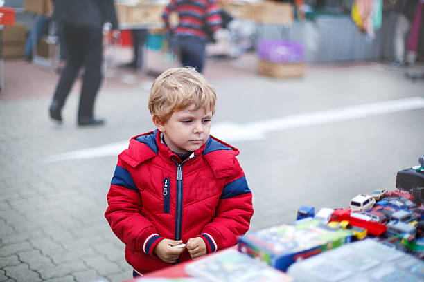 Beautiful toddler boy in red clothes on flea market