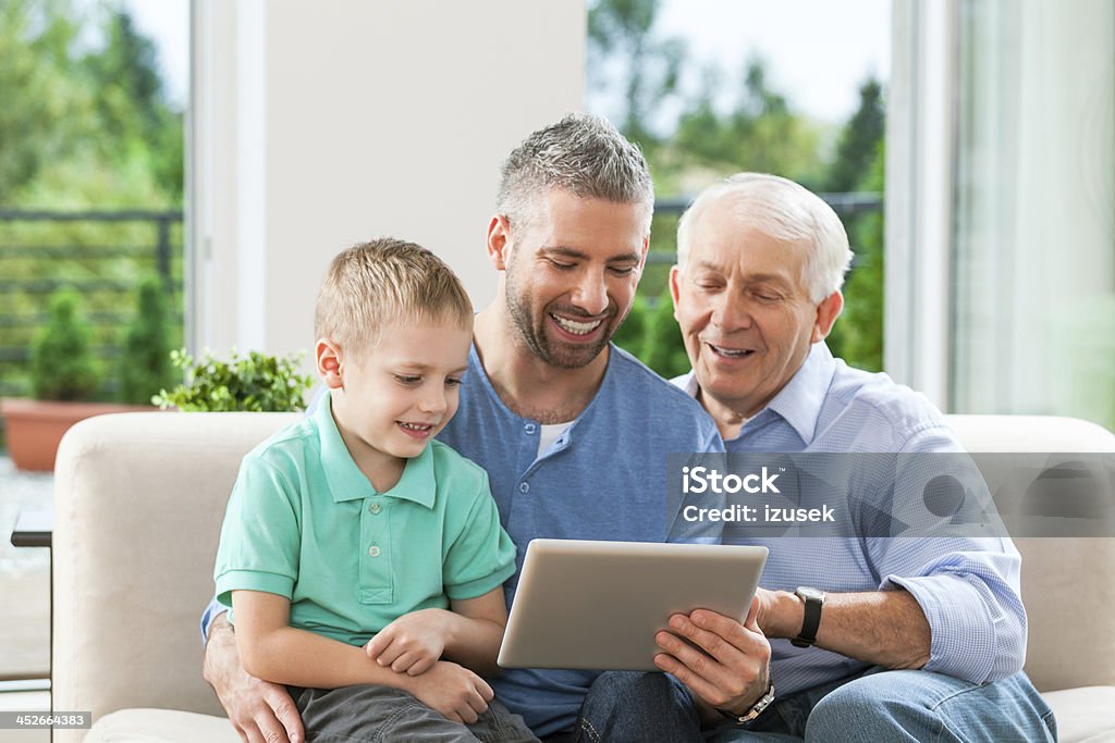 Three generation family with digital tablet Little boy, father and grandfather sitting on sofa at home and using a digital tablet together. 30-34 Years Stock Photo