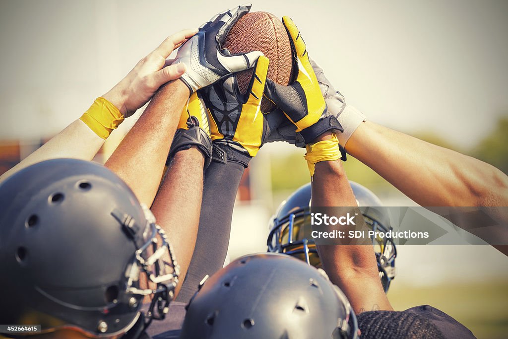 Fútbol americano Pro football players en huddle retención de bola - Foto de stock de Abrazo de grupo libre de derechos