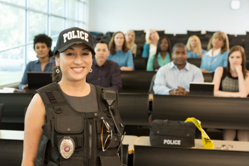 Latin policewoman speaks to police cadets in lecture hall;  or policewoman gives safety presentation to local community.