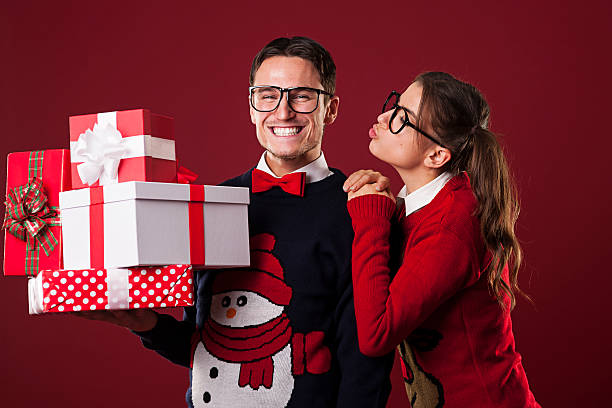 Nerdy woman kissing her boyfriend in christmas time Nerdy woman kissing her boyfriend in christmas time vintage nerd with reindeer sweater stock pictures, royalty-free photos & images