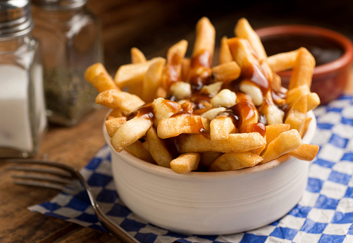 Classic French Canadian poutine with french fries, gravy, and cheese curds on a rustic tabletop.