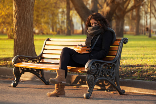 Young sad woman sitting alone on a park bench
