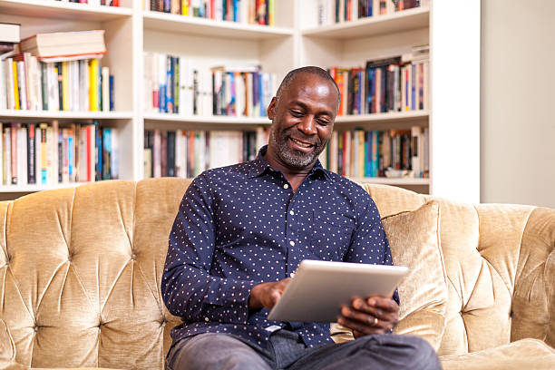 istock Happy man with digital tablet sitting on couch 452695923