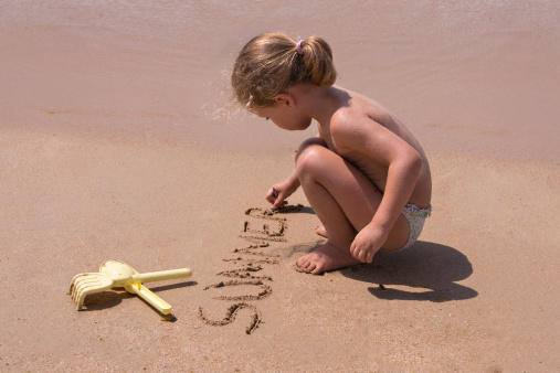 Girl writing in the sand on the beach