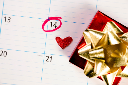 February calendar with focus on the 14th, Valentine's Day.  A glitter heart marks the 14th. Gift box to side.