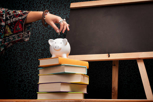 istock Teaching the value of saving: adding coin to classroom piggybank 452708825