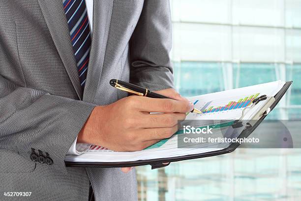 A Man Writing With A Ballpoint Pen On A Chart On A Clipboard Stock Photo - Download Image Now