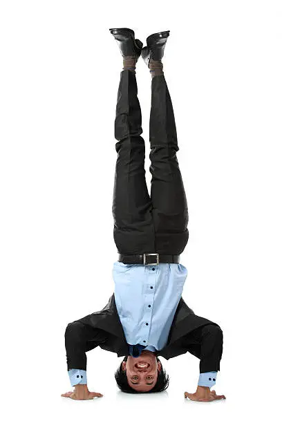 Full length of business man doing headstand isolated over white background