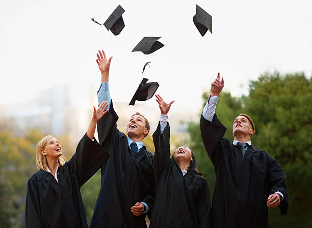 Here's to the rest of our lives! A group of students throwing their caps into the air after graduation graduation throwing cap stock pictures, royalty-free photos & images