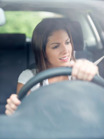 Beautiful woman driving using the Side Mirror. Natural Beauty. Nikon D800e. Converted from RAW. Copy Space at the Bottom.