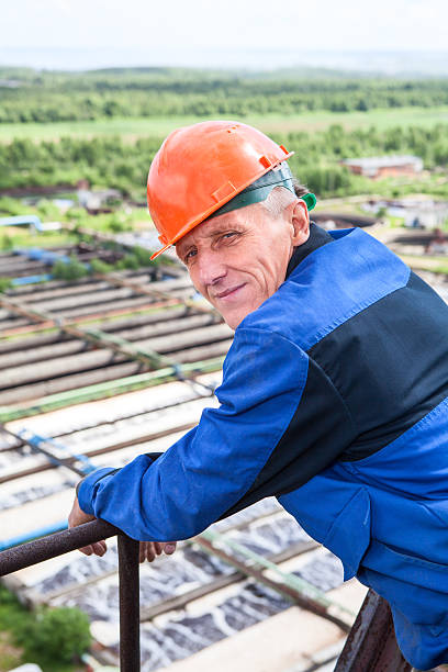 manuale operaio in uniforme blu e arancione elmetto da cantiere guardando indietro - engineer environment orange manual worker foto e immagini stock