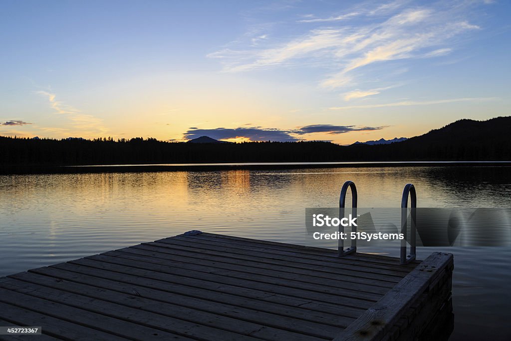 Dock At Sunset After the day's swimmers have departed, a dock sits silent and solitary at sunset Back Lit Stock Photo