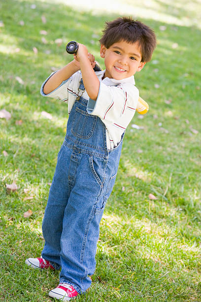 istock Young boy holding baseball bat outdoors smiling 452726377