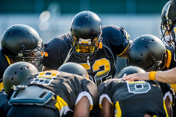 Football huddle American football players in a team huddle intercepting stock pictures, royalty-free photos & images