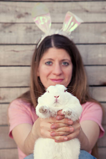 istock Beautiful young woman with bunny ears holding a rabbit 452762879