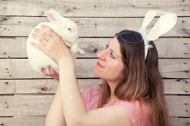 istock Beautiful young woman as easter bunny holding a rabbit 452763317